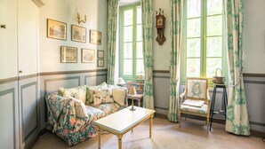 Une pièce avec un canapé à motifs floraux, une table en bois et une horloge ancienne.