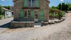 A stone house with green shutters, a small porch, and a gravel driveway. - Tranquil Villa in Cévennes (Courry)