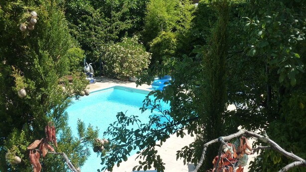 A clear blue swimming pool surrounded by lush greenery, with a few lounge chairs and a small deck area. - Tranquil Villa in Cévennes (Courry)