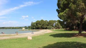 Um parque com um lago, áreas gramadas e árvores.