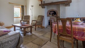 A cozy living room with a fireplace, wooden furniture, and a dining table. - Cottage in an old remote farmhouse (Giroux)