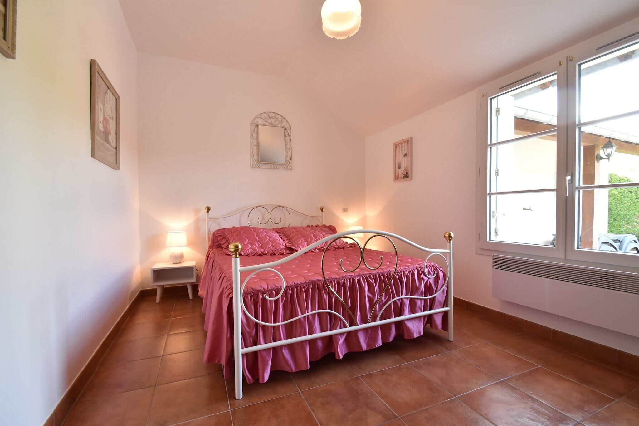Een slaapkamer met een bed, een nachtkastje, een raam en een spiegel aan de muur.