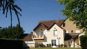 Une maison à deux étages avec un balcon, une pelouse et un ciel dégagé.