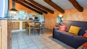 A kitchen with wooden beams, a dining area, and a sofa with cushions.