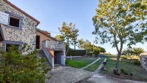 A stone house with a small porch and a paved driveway.