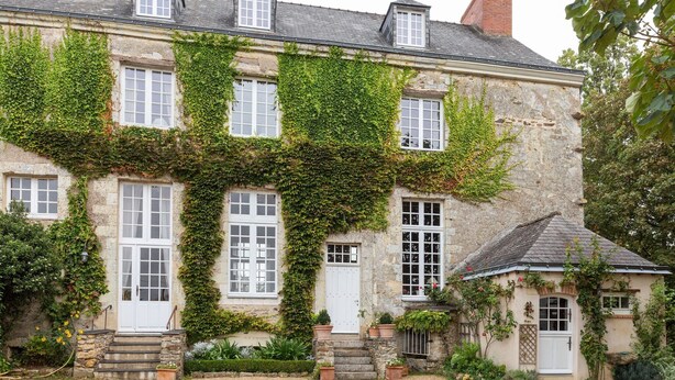 A stone building with ivy-covered walls and multiple windows.