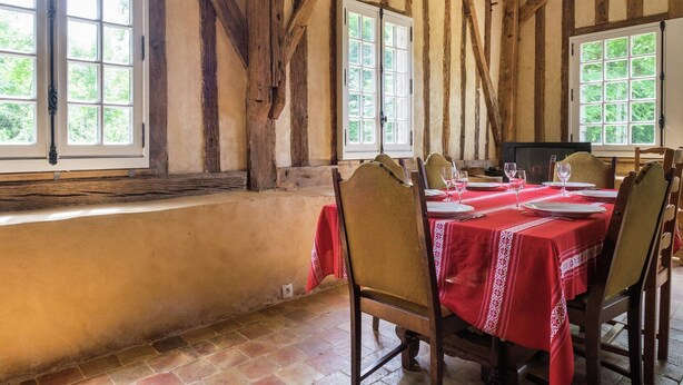 A dining area with a wooden ceiling, large windows, and a red tablecloth. - Historic Home Saint-Aignan by Lake (Saint-Aignan)