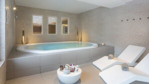 A modern spa area with a large bathtub, two lounge chairs, and a small table with toiletries. - Apartment in Beaufort with Spa Access (Beaufort)