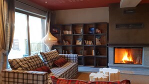 A cozy living room with a fireplace, a sofa set, a bookshelf, and a decorative lamp. - Apartment in Beaufort with Spa Access (Beaufort)