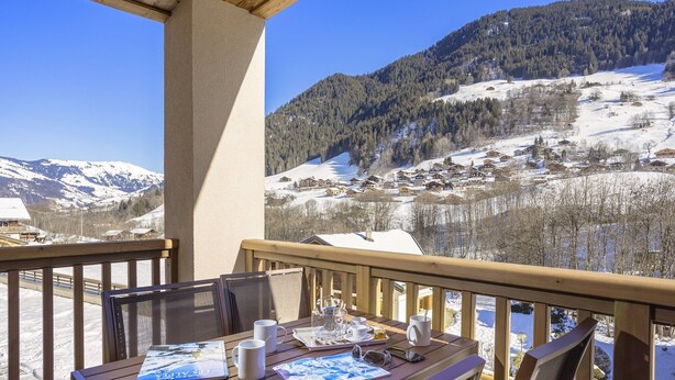 A wooden deck with a table set for a meal, overlooking a snowy mountain landscape. - Apartment in Beaufort with Spa Access (Beaufort)