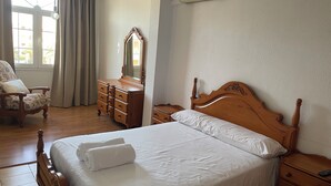 A bedroom with a wooden bed, a nightstand, a dresser, a chair, and a window with curtains. - Charming 3-bedroom townhome with AC, WiFi in lovely Retamar (Retamar)