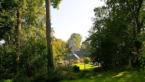 A church with a clock tower surrounded by lush greenery. - Bungalow in France near Castle & Hiking Trails (Saint Pierre le Vieux)
