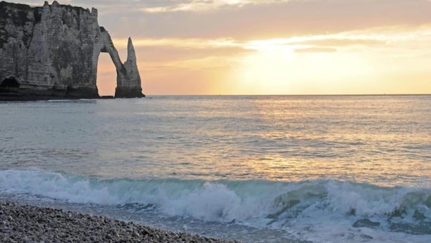 A coastal scene with a prominent rock formation and a sunset over the ocean. - Bungalow in France near Castle & Hiking Trails (Saint Pierre le Vieux)
