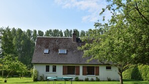 A two-story house with a sloped roof, a small balcony, and a green trampoline in the front yard. - Bungalow in France near Castle & Hiking Trails (Saint Pierre le Vieux)