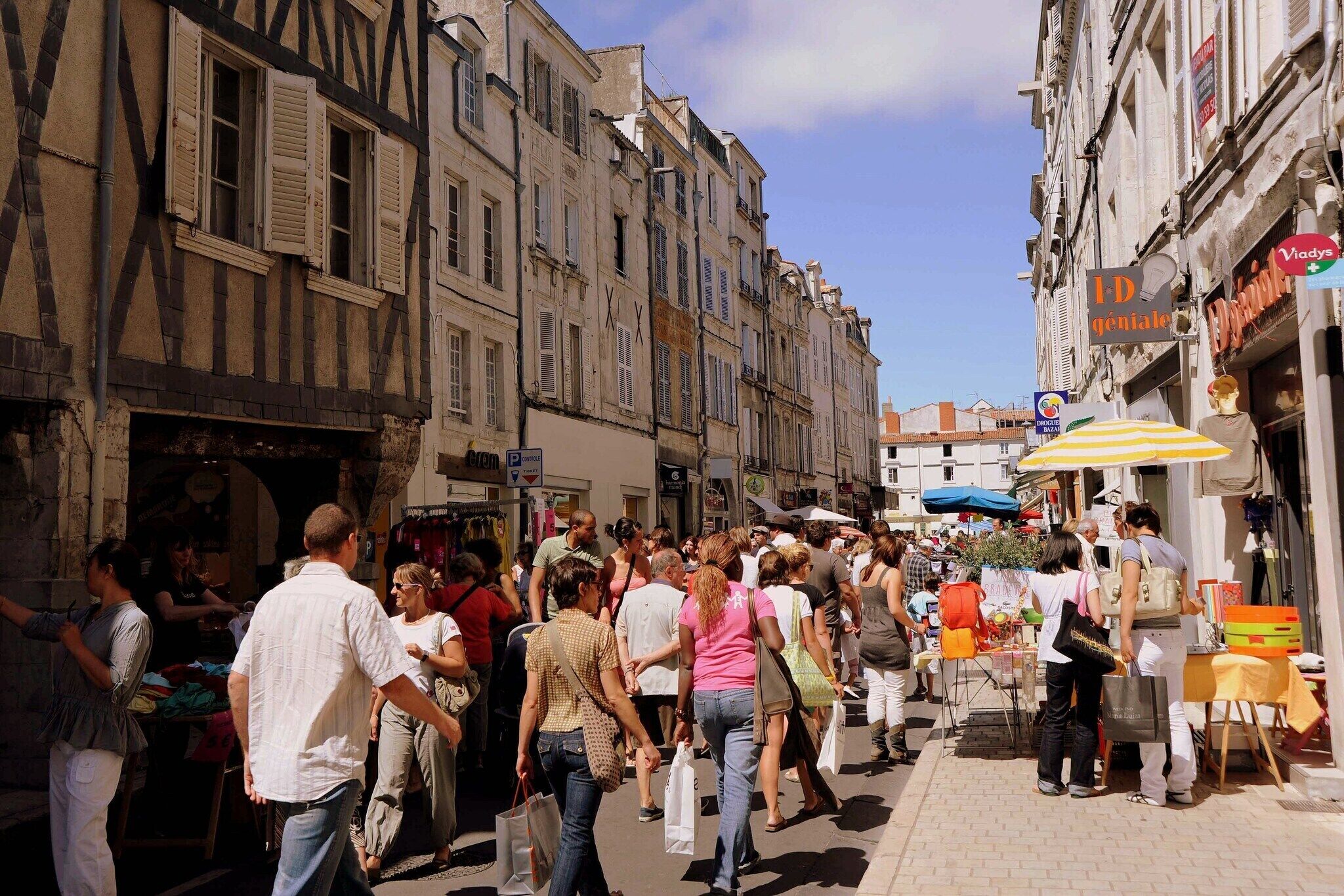Une rue animée, où l’on croise de nombreux piétons et où se trouvent des cafés avec terrasses.
