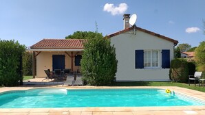 Une maison avec une piscine, une terrasse avec des chaises et une antenne parabolique.