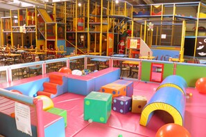 A children's play area with colorful play structures, tables, and chairs.