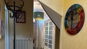 A hallway with a radiator, a coat rack, a staircase, and a colorful wall decoration. - The bird house (Tours)