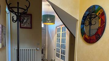 A hallway with a radiator, a coat rack, a staircase, and a colorful wall decoration.