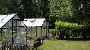 Ein Gewächshaus mit Holzzaun und Gartenbereich.