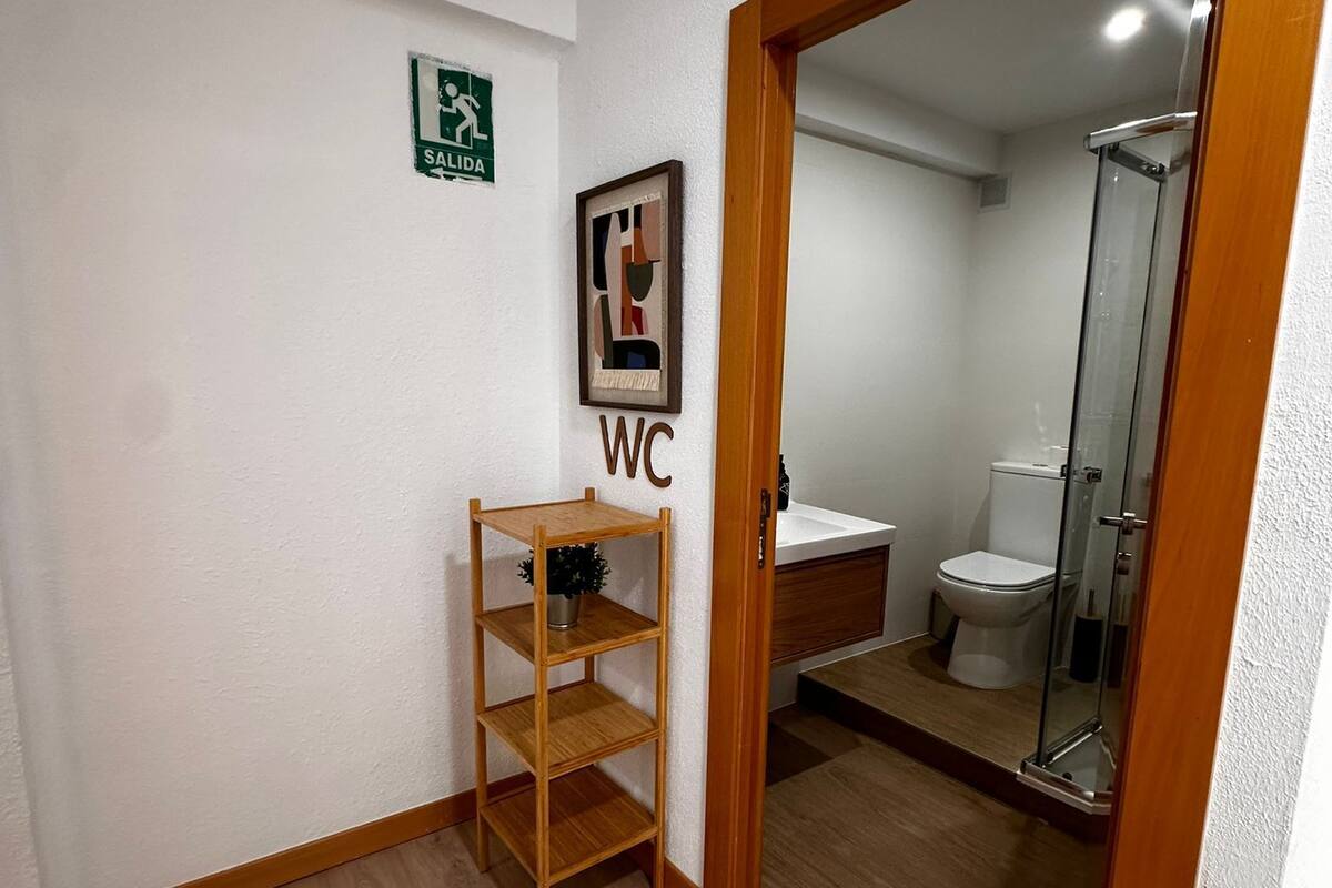 A bathroom with a wooden shelf, a WC sign, and a shower area.