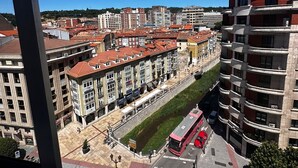 A high-rise building with a red bus in front. - HOSTAL ATUAIREHOME BURGOS (Burgos)