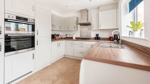 A modern kitchen with white cabinetry, a built-in oven, a stove, and a sink. - Your Stylish, Spacious 4 Bedroom, 3 Bathroom, home-from-home near all amenities. (Colchester)