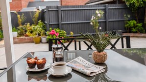 A glass table with a newspaper, a cup of coffee, and two muffins. - Your Stylish, Spacious 4 Bedroom, 3 Bathroom, home-from-home near all amenities. (Colchester)