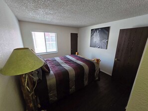 Een slaapkamer met een bed, een raam, een deur en een wanddecoratie van een zebra.