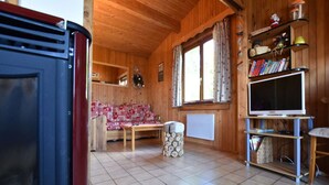 Ein gemütliches Blockhaus-Interieur mit Holzboden, einer Couch, einem Fernseher und einem Bücherregal.