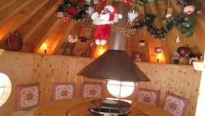 A cozy room with a wooden ceiling, a table with a lamp, and festive decorations including a Santa figure. - Ventron Chalet with Hill Views (Ventron)