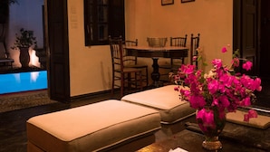 Ein Zimmer mit Pool, Esstisch mit Stühlen, einer Bank und einer Vase mit Blumen.