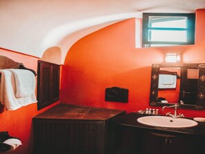 A bathroom with a red wall, a wooden cabinet, a sink, and a mirror.