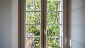 Une fenêtre donnant sur un jardin et des arbres.
