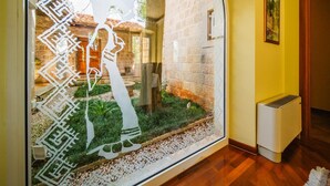 Une pièce avec une grande fenêtre, un radiateur et un tableau accroché au mur.