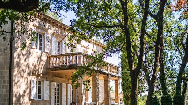 Un bâtiment historique doté d’une façade en pierre, de grandes fenêtres et d’un balcon orné de balustrades décoratives.