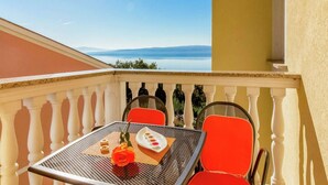 A balcony with a table, chairs, and a rose.