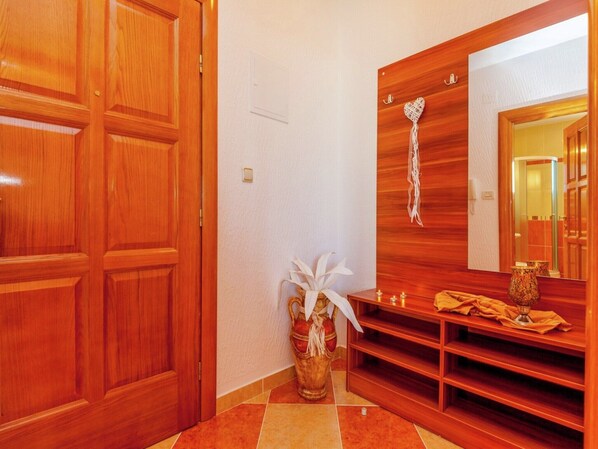 A wooden door, a mirror, a vase with white flowers, and a shelf with candles.