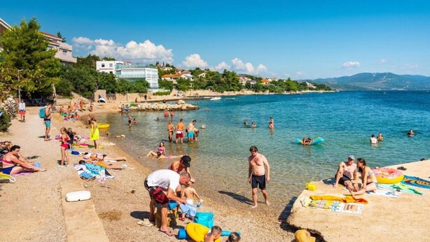 Une plage où des gens se prélassent au soleil et se baignent.