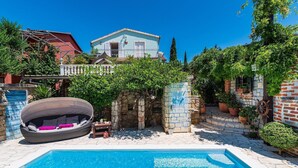 Une piscine avec un fauteuil en osier et un mur en pierre.