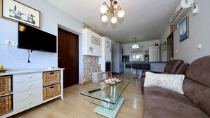 Un salon avec une table basse en verre, un canapé marron, un téléviseur fixé au mur et une cheminée.
