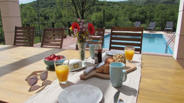 A breakfast table with a view of a pool and trees, including a bowl of fruit, croissants, and a vase of flowers. - Villa in Tijarica with Private Pool (Tijarica)