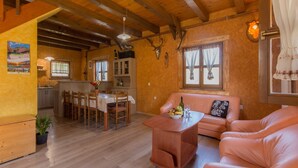 A cozy living room with a wooden ceiling, a dining area with a table and chairs, and a kitchen in the background. - Holiday Home in Brod Moravice with Pool (Brod Moravice)