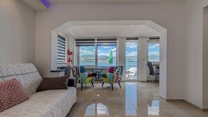 Uma sala de estar ampla com sofá, mesa de centro e vista para o oceano através de grandes janelas.