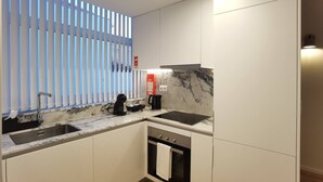 Una cocina moderna con horno integrado, un lavamanos y una cafetera.