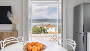 Cozinha moderna com uma janela grande, geladeira e área de refeições com mesa e cadeiras.