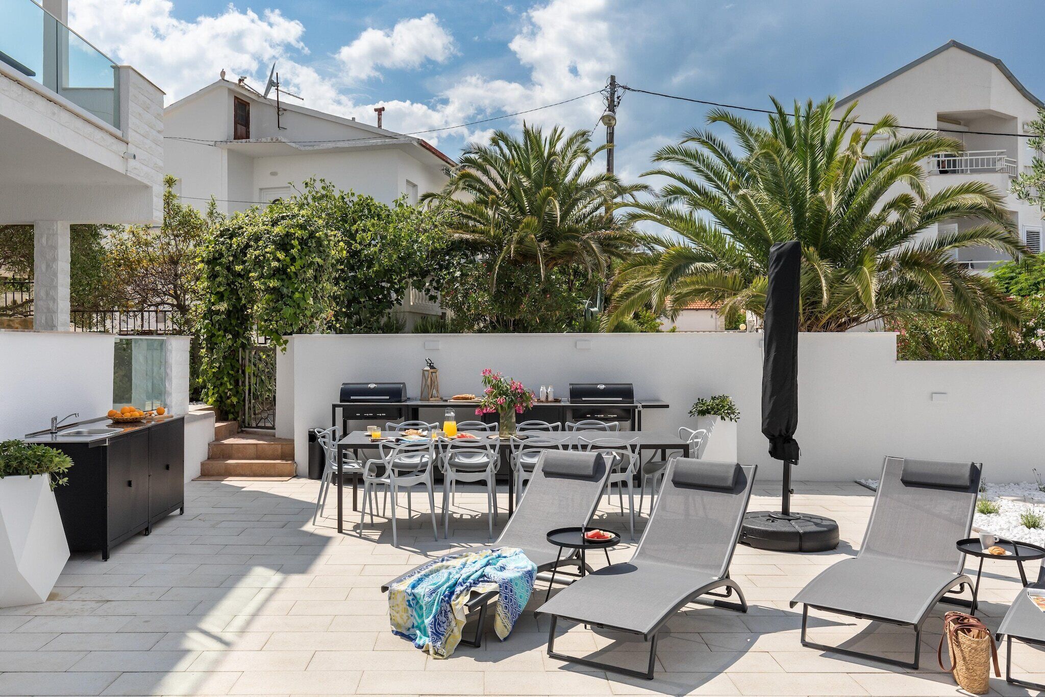 Eine Außenpatio mit Grill, Liegestühlen und Essbereich.