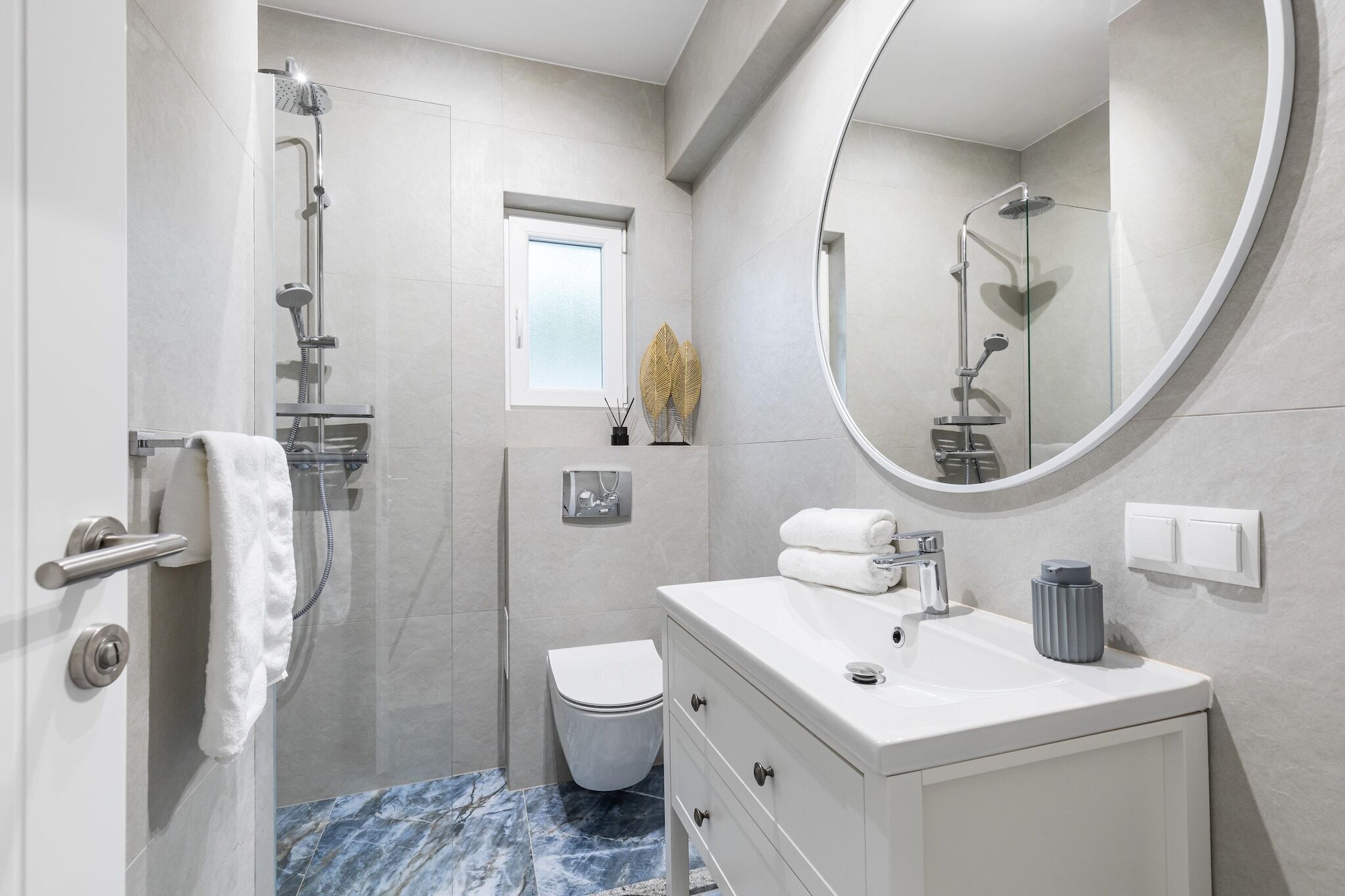 A modern bathroom with a glass-enclosed shower, a white vanity with a mirror, and a toilet.