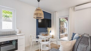 Une cuisine moderne avec des meubles blancs, un four encastré et un coin repas comprenant des chaises blanches et une table ronde.