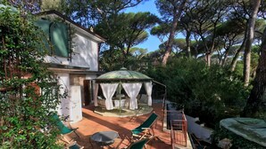 Un patio con mobili da esterno, una zona salotto coperta e una casa con un tenda verde.